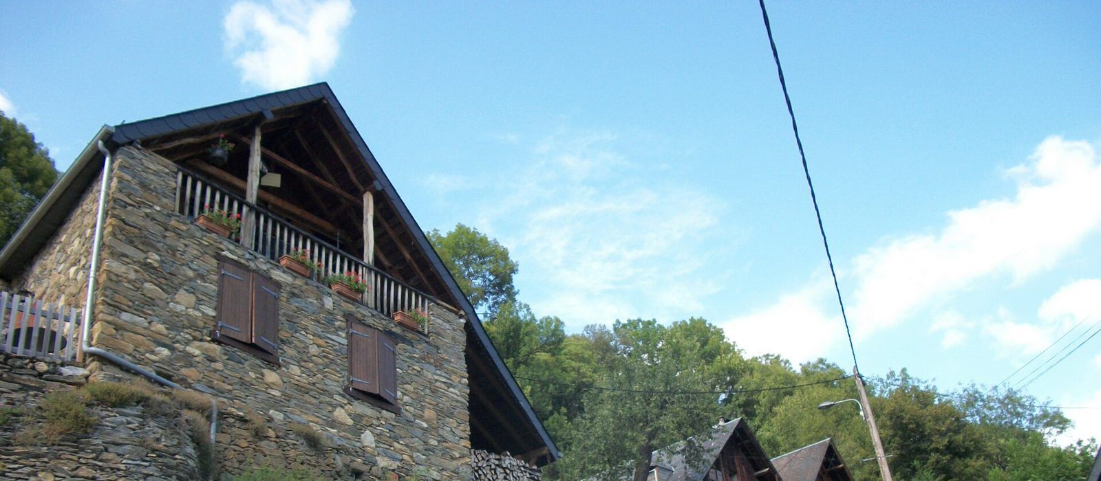 Maison de pierre à toiture d'ardoises, avec un balcon en bois